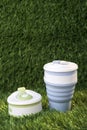 Modern blue collapsible silicone cup on the background of green nature. reusable thermos bottle. No waste