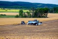 A modern blue combine harvester stands on a field where the spring grain crop has just been harvested. Farmers perform small Royalty Free Stock Photo