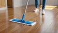 Modern blue mop with microfiber standing on the wooden parquet floor. Process of cleaning room. Concept supporting house hygiene Royalty Free Stock Photo