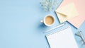 Modern blue office desk with blank notepad, cup of coffee, pink paper notebook, glasses, envelope, flowers. Minimal style feminine Royalty Free Stock Photo