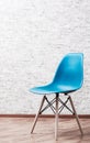 Modern blue plastic chair in an empty room with wooden floor on gray Brick Wall Background Royalty Free Stock Photo