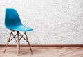 Modern blue plastic chair in an empty room with wooden floor on gray Brick Wall Background Royalty Free Stock Photo