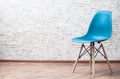 Modern blue plastic chair in an empty room with wooden floor on gray Brick Wall Background Royalty Free Stock Photo