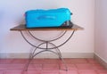 Modern blue rolling suitcase on wooden stand
