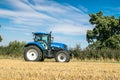 Modern blue tractor in harvest field