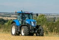 Modern blue tractor in harvest field