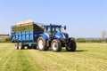 Modern blue tractor pulling a trailer in grass field