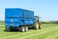 Modern blue tractor pulling a trailer in grass field Royalty Free Stock Photo