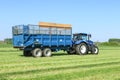 Modern blue tractor pulling a trailer in grass field Royalty Free Stock Photo