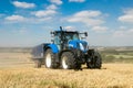 Modern blue tractor pulling a trailer in harvest field Royalty Free Stock Photo