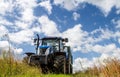 Modern blue tractor pulling a trailer in harvest field Royalty Free Stock Photo