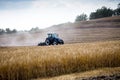 A modern blue tractor with a trailed disc harrow with a husking roller plows a field on which the spring grain crop has just been Royalty Free Stock Photo