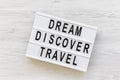 Modern board with text `Dream Discover Travel` word on white wooden background, top view. From above, flat lay Royalty Free Stock Photo