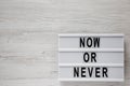 Modern board with text `Now or never` on a white wooden surface. Flat lay, overhead, from above. Space for text Royalty Free Stock Photo