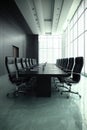 modern boardroom with sleek black table, high back chairs, and large windows creating professional atmosphere Royalty Free Stock Photo