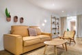 Modern boho interior of living room at cozy apartment with beige sofa, wooden table, wicker chair. Stylish home decor.