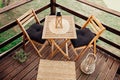 Modern boho style small wood balcony seating corner with wooden garden furniture, soft black pillows. Royalty Free Stock Photo