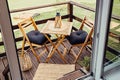 Modern boho style small wood balcony seating corner with wooden garden furniture, soft black pillows. Royalty Free Stock Photo