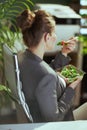 modern bookkeeper woman in green office eating salad