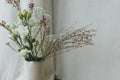 Modern bouquet in vase against tulle and rustic wall. Stylish spring flowers, eustoma, gypsophila and chamelaucium