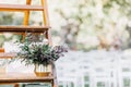 Modern bouquet in vase on wooden shelf for outdoor wedding ceremony on green lawn in summer