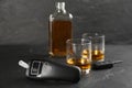 Modern breathalyzer, car key and alcohol on black table Royalty Free Stock Photo