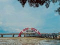 A modern bridge with a distinctive red and white arch spans a body of water. Royalty Free Stock Photo
