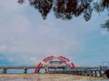 A modern bridge with a distinctive red and white arch spans a body of water. Royalty Free Stock Photo