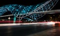 Modern bridge with neon light and blurry car headlights at night in Georgia