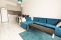 Modern bright and cozy living room interior design with sofa, dining table and kitchen. Grey and turquoise blue studio apartment