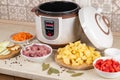 Modern, light multi cooker and products on table in kitchen. Cooking stewed potatoes with meat in multicooker Royalty Free Stock Photo