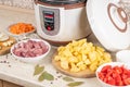 Modern, light multi cooker and raw products on table in kitchen. Cooking stewed potatoes with meat in multicooker Royalty Free Stock Photo