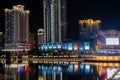 Modern bright night illuminated riverside with commercail buildings and reflections