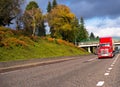 Bright red big rig semi truck transporting container on flat bed Royalty Free Stock Photo