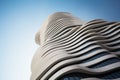 Modern building with futuristic design, abstract curve shapes on blue sky background. Low angle of high-rise tower, wavy geometric Royalty Free Stock Photo