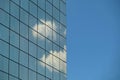 Modern building glass facade reflecting cloudy blue sky