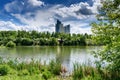 Modern building is reflected in lake in city Park. Summer Sunny day in a city with beautiful clouds Royalty Free Stock Photo