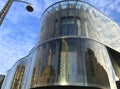 Modern building with rounded glass front against a blue sky with white clouds Royalty Free Stock Photo