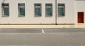 Modern building with a row of new PVC windows. Yellow concrete sidewalk and asphalt road in front.