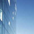 A modern building with a sleek glass facade reflecting the sky, creating a seamless