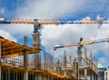 Modern building tower cranes are used in the construction of a building under construction against a blue, cloudy sky Royalty Free Stock Photo