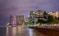 Modern buildings illuminated at night in Honolulu, Hawaii shot in long exposure near the sea