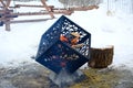 Modern burning fireplace in the shape of a metal cube outdoors in the park