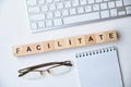 Modern business buzzword - facilitate. Top view on wooden table with blocks. Top view