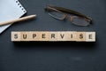 Modern business buzzword - supervise. Top view on wooden table with blocks. Top view