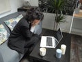 Modern business caucasian woman frustrated, crying, sitting on the sofa with a laptop and a cup of coffee