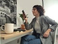 Modern business caucasian woman looking something on her phone with a cup of coffee, post-its and a laptop on her desk