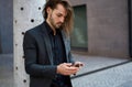 Outdoor portrait modern business guy in black suit using a smartphone for connection and chatting