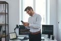 Modern business. Happy and successful trader in formal wear is looking at trading graphs and reports on his smartphone