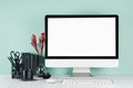 Modern business interior - workplace with blank computer display, black stationery, red plant, keyboard, mouse, coffee cup. Royalty Free Stock Photo